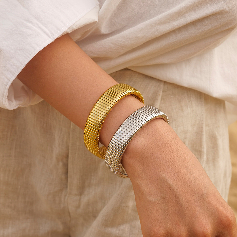 Aurora Luxe armbanden in gouden en zilveren kleuren, gedragen met een lichte, casual outfit. De tijdloze en verfijnde uitstraling van deze armbanden zorgt voor een luxueuze afwerking van elke look, perfect voor een elegante uitstraling op elke gelegenheid.