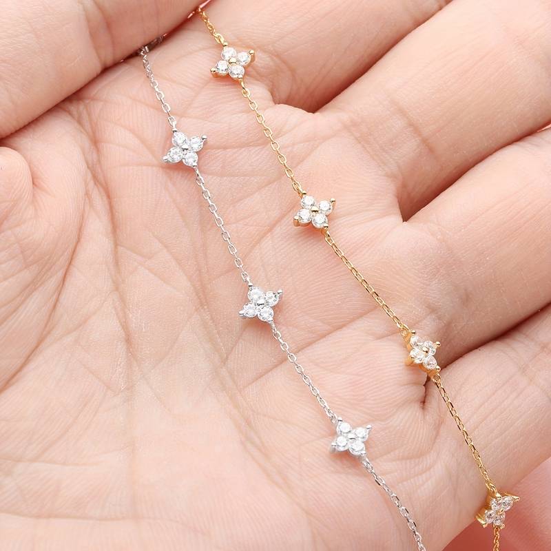 Close-up van de Perle Épure armband met delicate gouden schakels en sprankelende bloemvormige accenten, perfect voor een minimalistische en tijdloze uitstraling